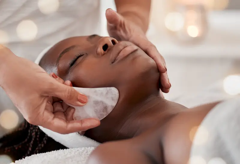 A woman enjoying a stone massage on her face