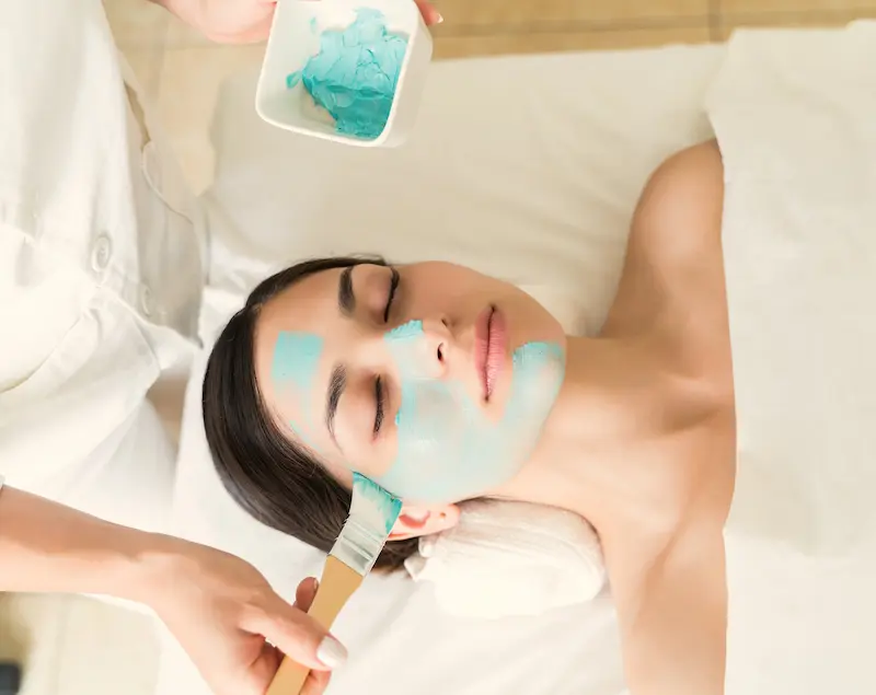 Blue cream being applied to woman's face