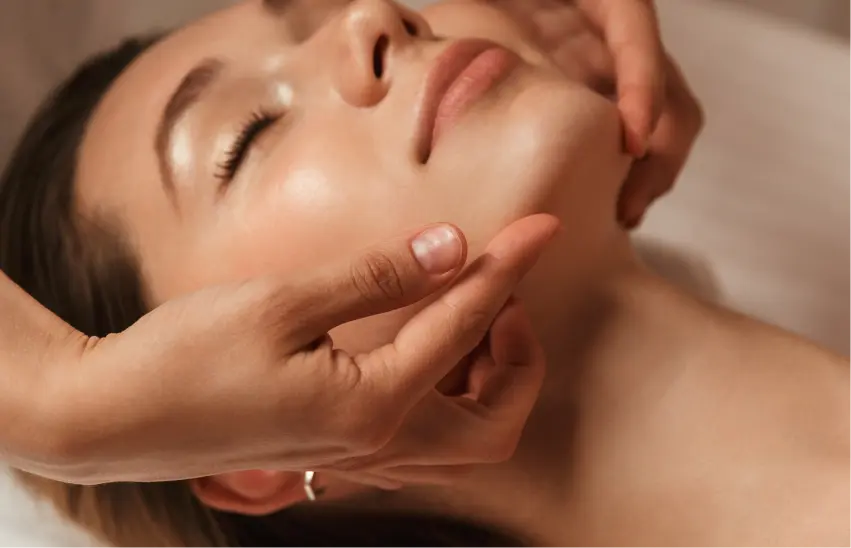 Hands massaging a woman's face